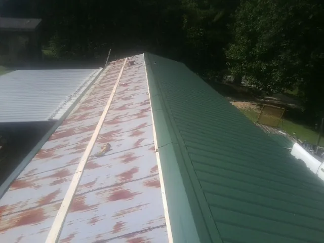 Old rusted panels beside newly installed green metal roofing — Wind Damage Roof Repair by Roofing Brothers in Roberta