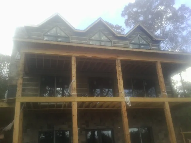Dormers and porch framing on a large log home under construction — Roof Coating work by our crew in Roberta