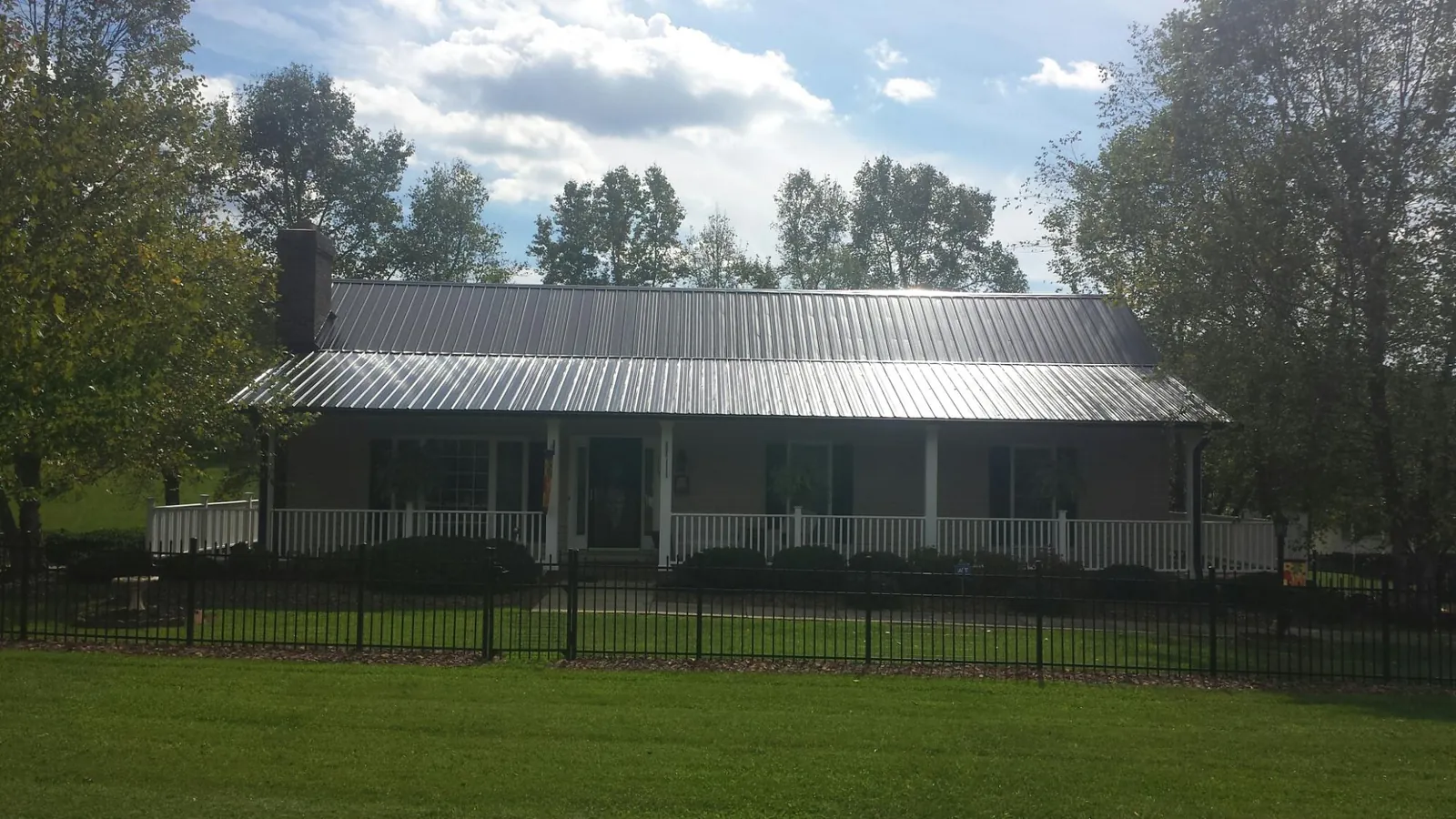 Gray metal roof on a brick ranch with a full width front porch — Gutter Guard Installation work by our crew in Roberta